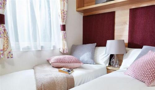 ペイントンにあるHoburne Devon Bay Stunning 3 bed static caravan with full deckingのベッドルーム1室(ベッド2台、ランプ付きテーブル付)