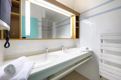 een witte badkamer met een wastafel en een spiegel bij Village Club Les Balcons des Pyrénées in Saint-Mamet