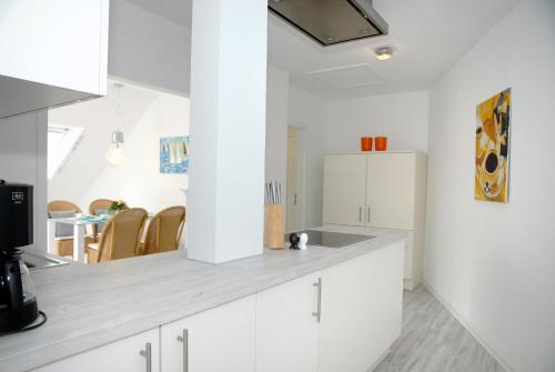 uma cozinha com armários brancos e um frigorífico branco em Seeschwalbe em Scharbeutz