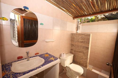 een badkamer met een wastafel, een toilet en een spiegel bij Isla Mulata, Islas del Rosario in Isla Grande