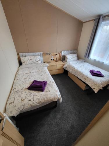 - 2 lits dans une chambre avec des oreillers violets dans l'établissement Red Squirrel Lodge, à Auchterarder