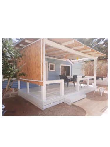 a pergola with a table and chairs on a patio at Shkutai Hottub Arava in Ẕofar