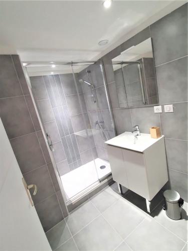 La salle de bains est pourvue d'une douche et d'un lavabo blanc. dans l'établissement Maison de ville des Arènes, à Arles