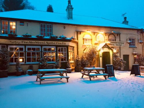 a building with benches in the snow in front of it at The New Forest Inn in Lyndhurst