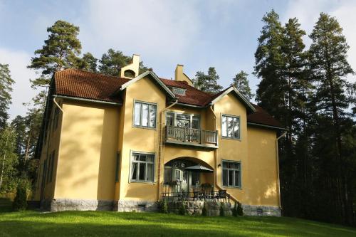 a yellow house with a balcony on the side of it at Villa Urhola, Kruunupuisto in Punkaharju