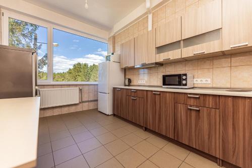 uma cozinha com armários de madeira e um frigorífico em Svečių namai pajūryje em Palanga