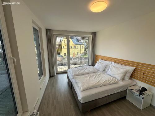 een slaapkamer met een bed en een groot raam bij Máchovo jezero apartmán J&J in Doksy