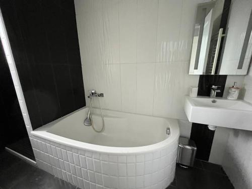 a white bathroom with a tub and a sink at Wasat YourHostHelper in Caen