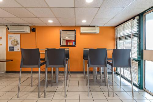 a conference room with black chairs and an orange wall at Premiere Classe Rouen Sud - Parc Des Expositions in Saint-Étienne-du-Rouvray