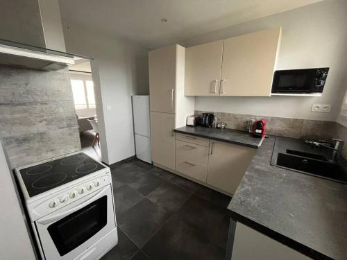 Il comprend une petite cuisine équipée d'une cuisinière et d'un réfrigérateur. dans l'établissement Wasat, Joli appt 3 chambres à Caen, à Caen