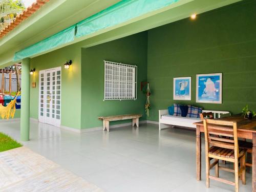 a room with a green wall with a bench and a table at Pousada Vila Tadeu in São João Batista do Glória