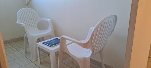two white chairs and a table with a tablet on it at Logement spacieux deux pièces à Baie Mahault in Baie-Mahault