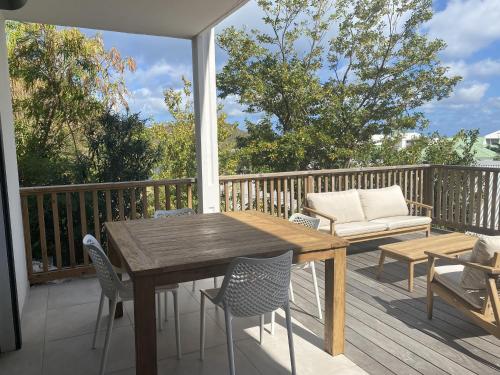 a porch with a wooden table and chairs on a deck at Cottage Cosy Duplex Anse Marcel, Vue mer et marina in Anse Marcel 