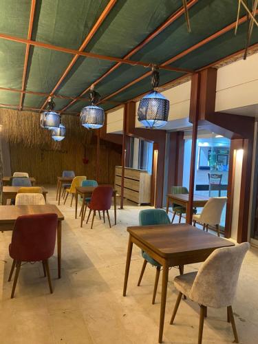 ein Esszimmer mit Tischen, Stühlen und Lichtern in der Unterkunft Marla Didim Otel in Didim