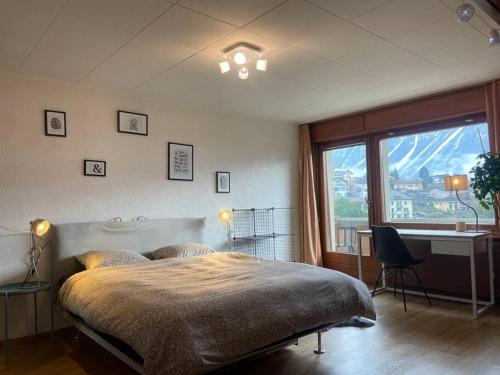 a bedroom with a bed and a desk and a window at Spacieux, situation idéale pour visiter le Valais in Veyras