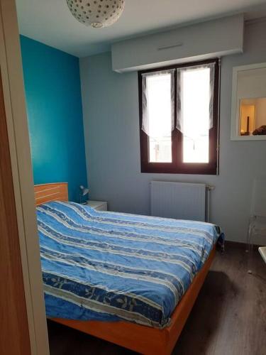 une chambre avec un lit aux murs bleus et une fenêtre dans l'établissement Appartement 10 mins Intra Muros, à Saint-Malo