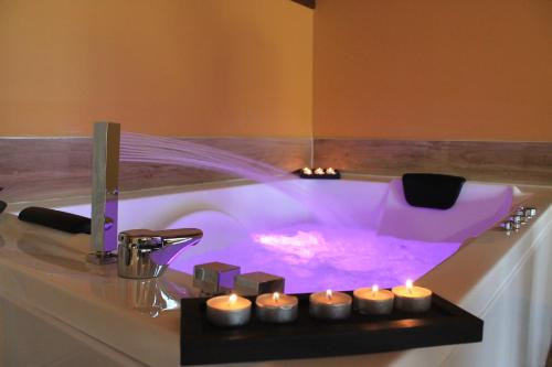 d'une baignoire avec éclairage violet et bougies. dans l'établissement Villas, El Mirador de Isla, à Isla