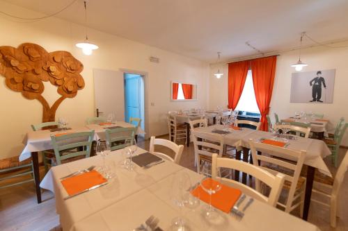 阿夸彭登泰的住宿－IL Borgo Ristorante Pizzeria Camere，餐厅配有白色桌椅和橙色餐巾