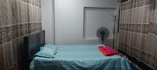 Habitación pequeña con cama y ventilador. en Kompass Homestay - Affordable AC Room With Shared Bathroom in Naya Paltan Free WIFI en Dhaka