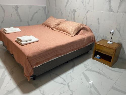 Una cama con dos toallas y una mesita de noche. en WHITE HOUSE en San Salvador de Jujuy