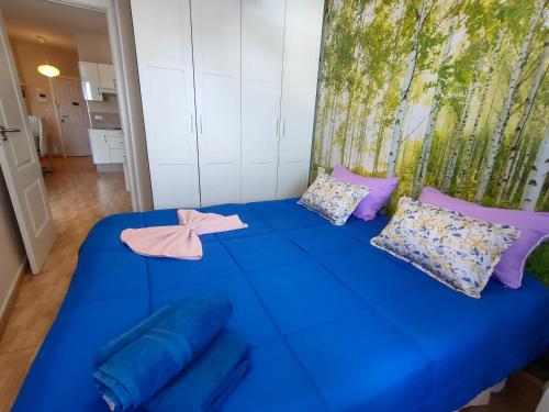 een blauw bed met kussens en een roze strik erop bij Precioso apartamento en Los Cristianos in Los Cristianos