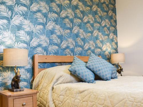 um quarto com uma cama com papel de parede azul e branco em Leveret Lodge em Leavenheath