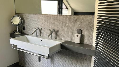 uma casa de banho com um lavatório branco e um espelho. em Ikigai em Oud-Turnhout