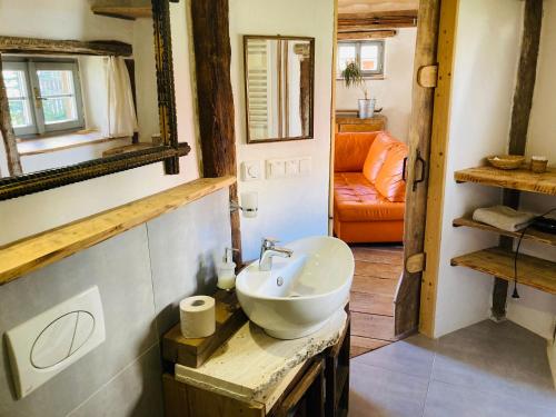 baño con lavabo y sofá naranja en Domček pod Botanickou záhradou en Banská Štiavnica