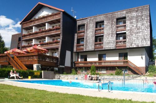un hôtel avec une piscine en face d'un bâtiment dans l'établissement Hotel Pavla Vysočina, à Nové Město na Moravě