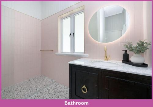 ein rosafarbenes Bad mit einem Waschbecken und einem Spiegel in der Unterkunft Harold Street 139 in Townsville