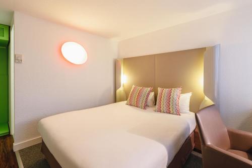 a bedroom with a large white bed and a chair at Campanile Lyon Bron Eurexpo in Bron