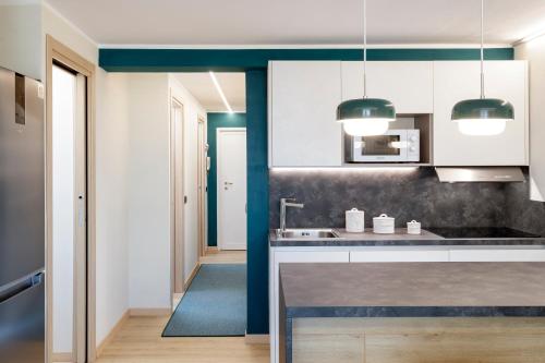a kitchen with white cabinets and a blue wall at HelloCHALET - Croix du Cervin - 150mt from Cretaz chairlift, central living in Breuil-Cervinia