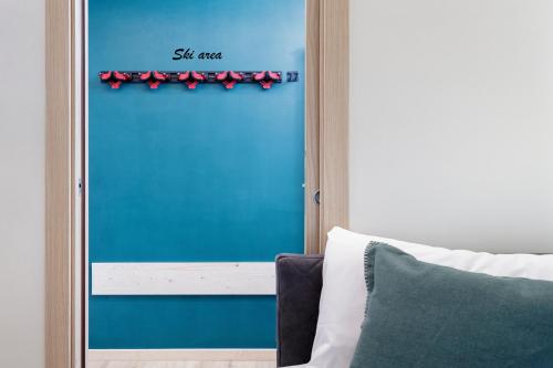a blue door with red bows on it next to a bed at HelloCHALET - Croix du Cervin - 150mt from Cretaz chairlift, central living in Breuil-Cervinia