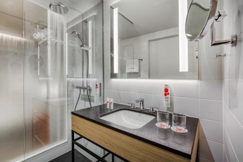 uma casa de banho com um lavatório e um chuveiro em IntercityHotel Karlsruhe em Karlsruhe