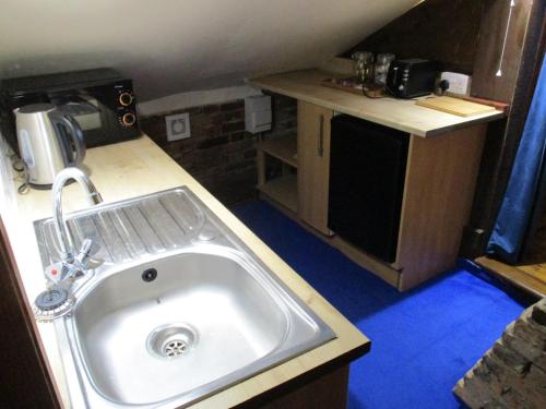 uma pequena cozinha com um lavatório num quarto em Bridge Stores em Fritton Norfolk