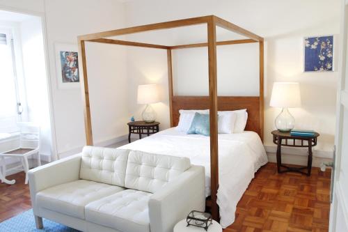 a bedroom with a canopy bed and a white couch at Magnolia Guesthouse in Lisbon