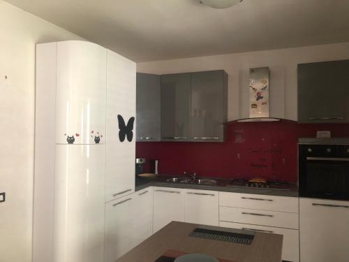 a kitchen with white cabinets and a red wall at IL PANORAMA in Altofonte