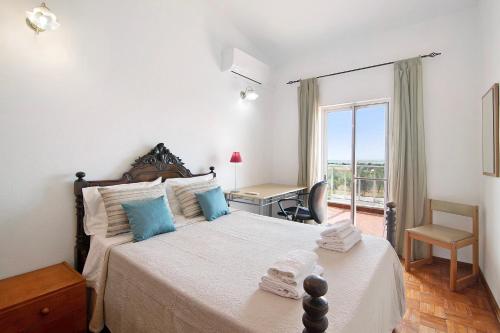 Schlafzimmer mit einem Bett, einem Schreibtisch und einem Fenster in der Unterkunft Bela Vista Retreat - Lavender in Olhão