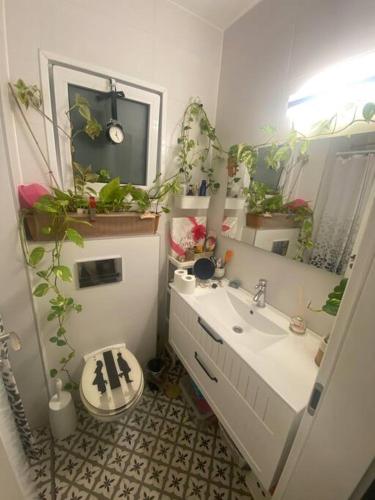 a bathroom with a sink and a toilet with plants at Sarin room in Yehud