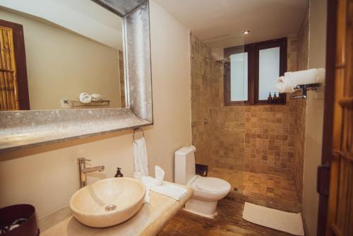 een badkamer met een wastafel, een toilet en een spiegel bij Selina Nosara in Nosara