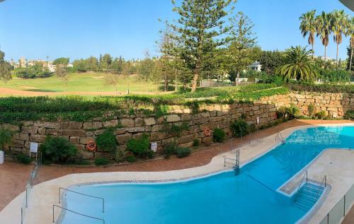 a large swimming pool next to a stone wall at Dream Apartment in Mijas Golf Limonar in Mijas Costa