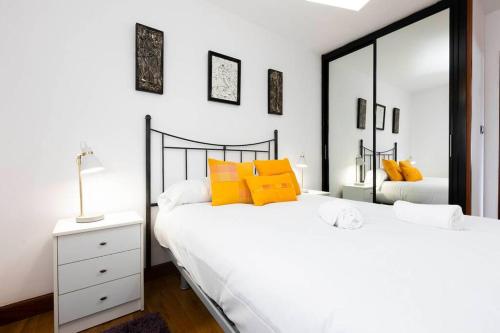 Duas camas num quarto branco com almofadas amarelas em Zurubi-gain. Basquenjoy em Hondarribia