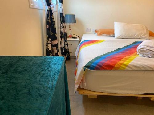 a bedroom with a bed with a rainbow blanket at Dudger home in Yehud