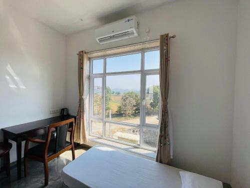 a room with a window and a desk and a bed at Vasant Vihar Resort in Kevadia