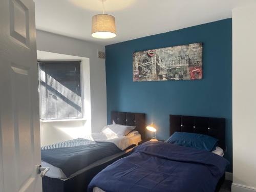 Duas camas num quarto com paredes azuis em Campion lodge em Hull