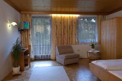 Schlafzimmer mit einem Bett, einem Stuhl und Fenstern in der Unterkunft Gasthof Pichler in Bruck an der Mur