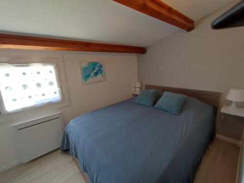 une chambre avec un lit bleu et une fenêtre dans l'établissement AZUR ET SOLEIL Jolie Maisonnette climatisée proche de la mer Richelieu Cap d'Agde, au Cap d'Agde