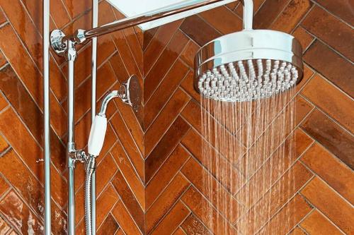 a shower with a shower head on a brick wall at Cottage in Pembroke, Close to beaches in Pembrokeshire