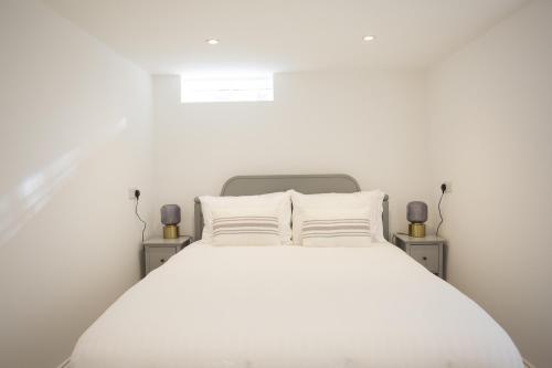 um quarto com uma cama branca com duas mesas de cabeceira em Garden View em Worthing