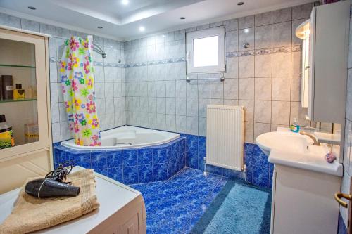 a blue bathroom with a tub and a sink at Villa George in Nea Peramos